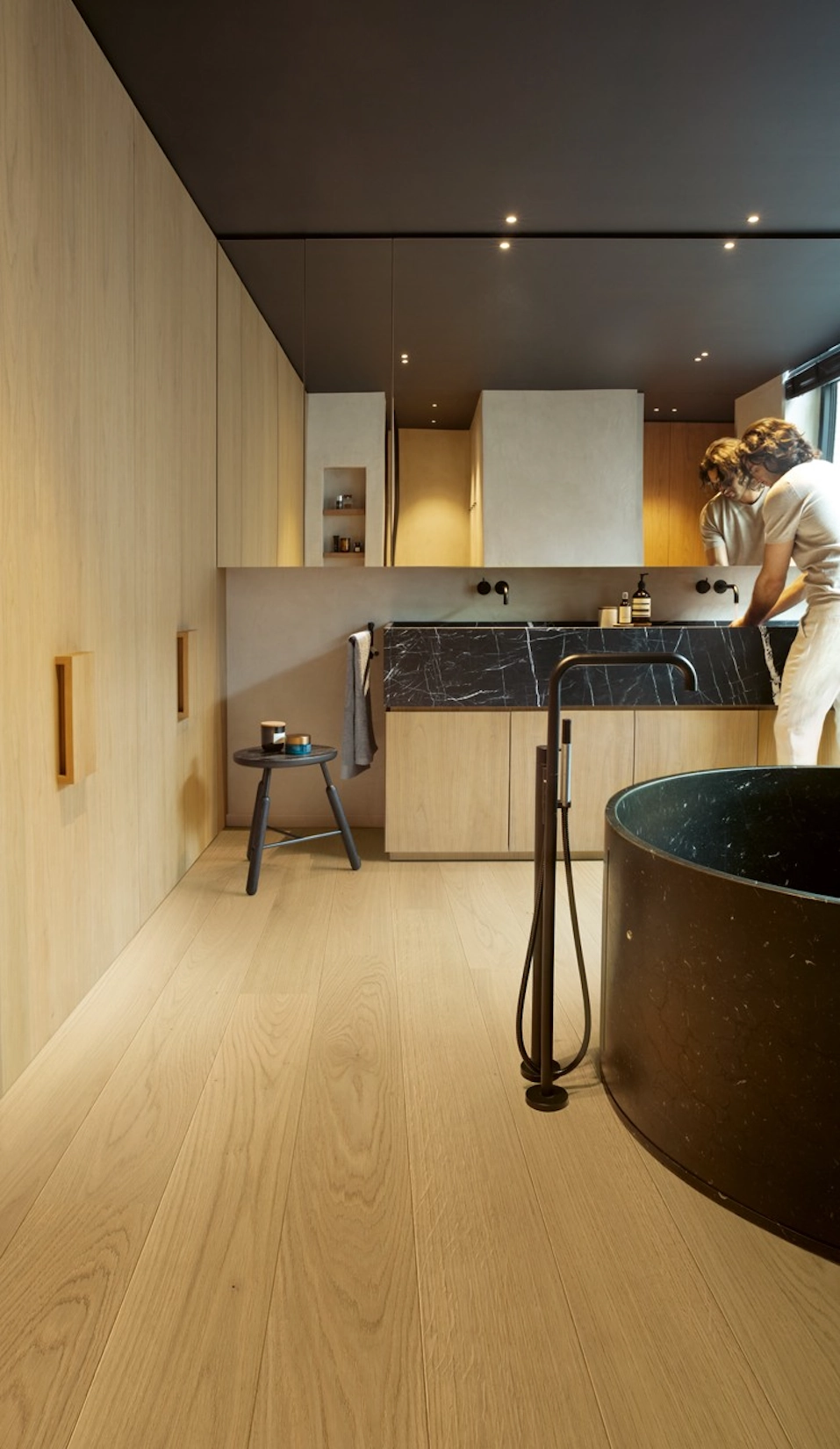 Oak slab kitchen with dark ceiling and freestanding bath