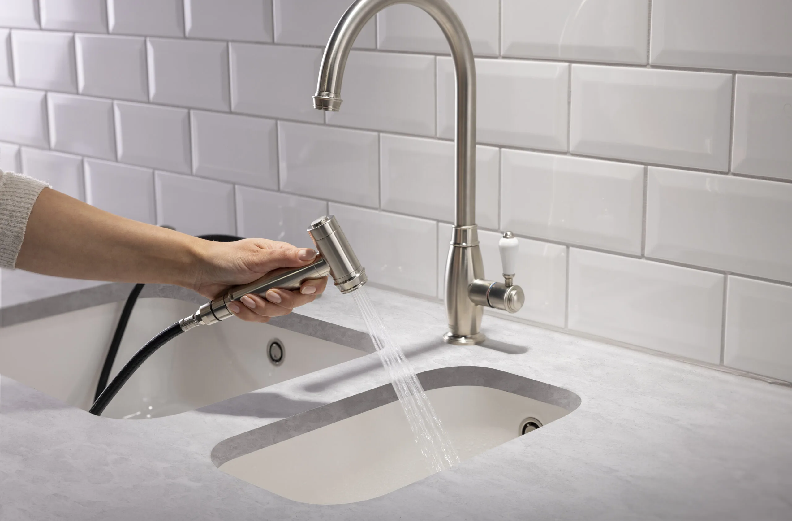 Pull-out spray kitchen tap in brushed steel against white metro tiles