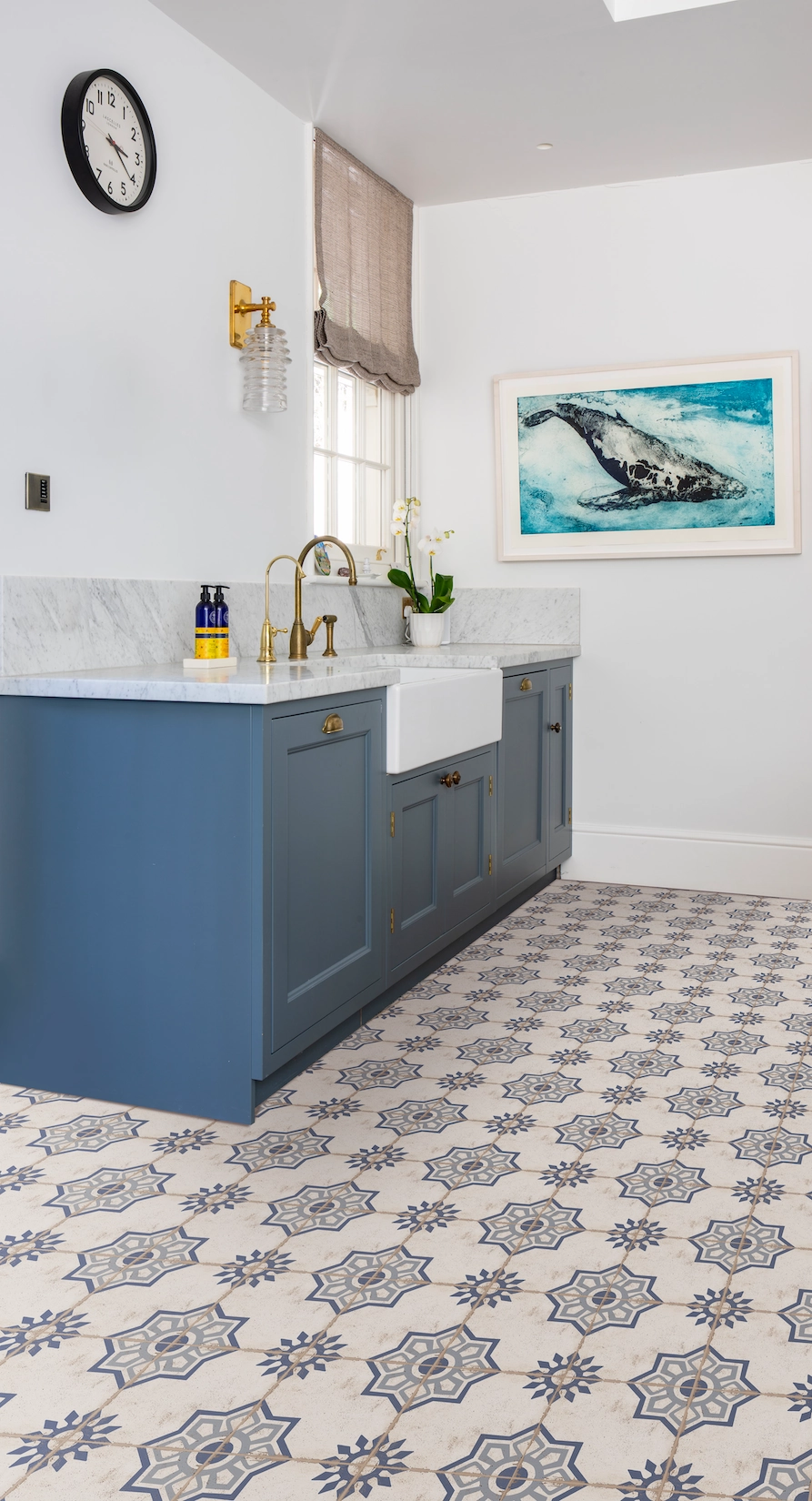Utility room with blue cabinetry and patterned tiled floor