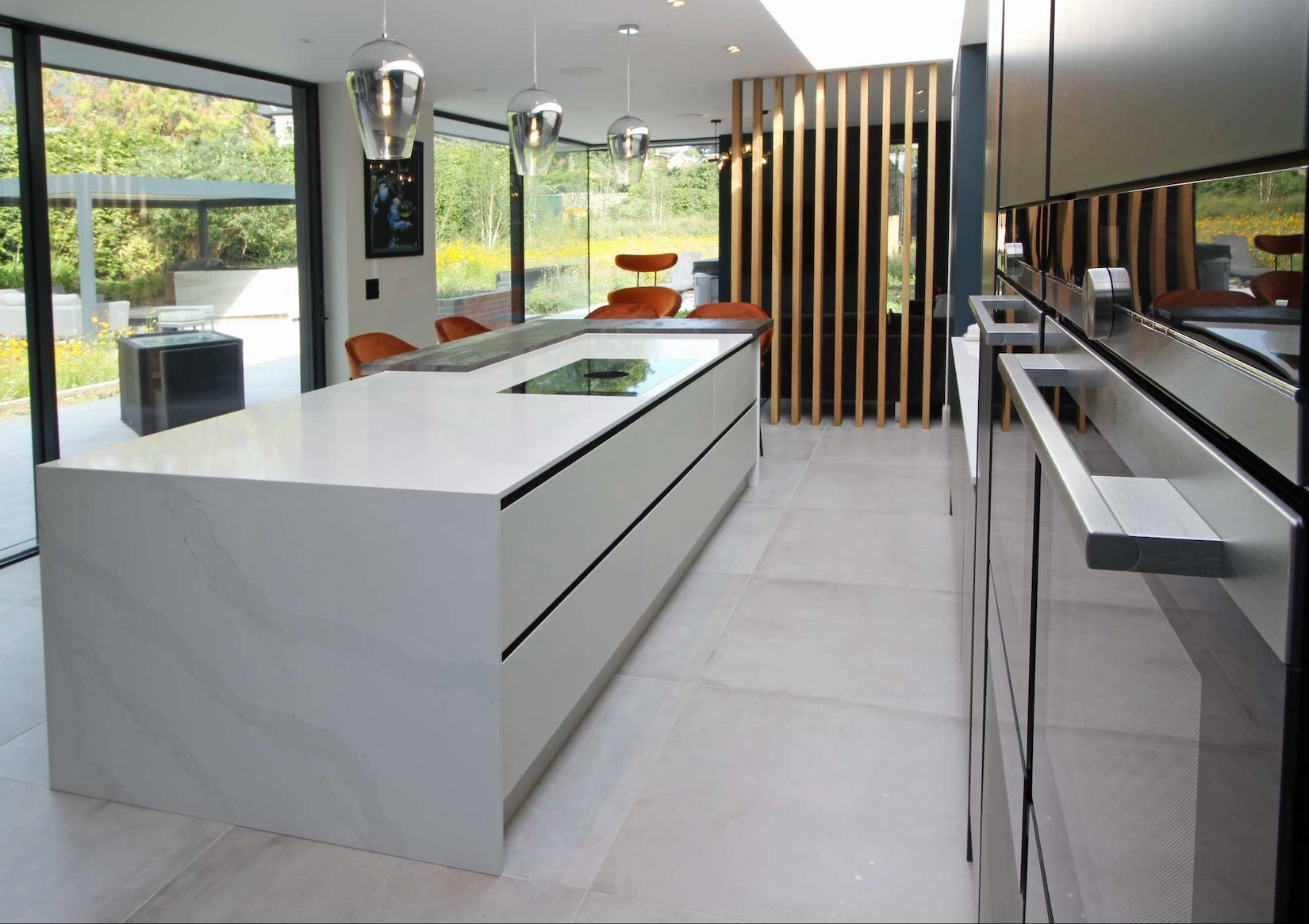 Handleless kitchen with white island and full height garden glazing