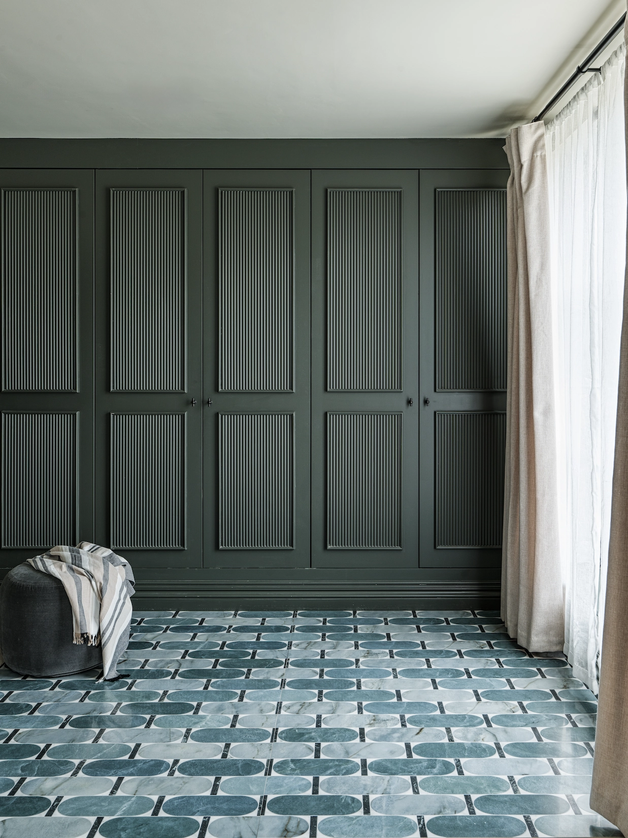 Dark green panelled fitted wardrobes with patterned floor tiles