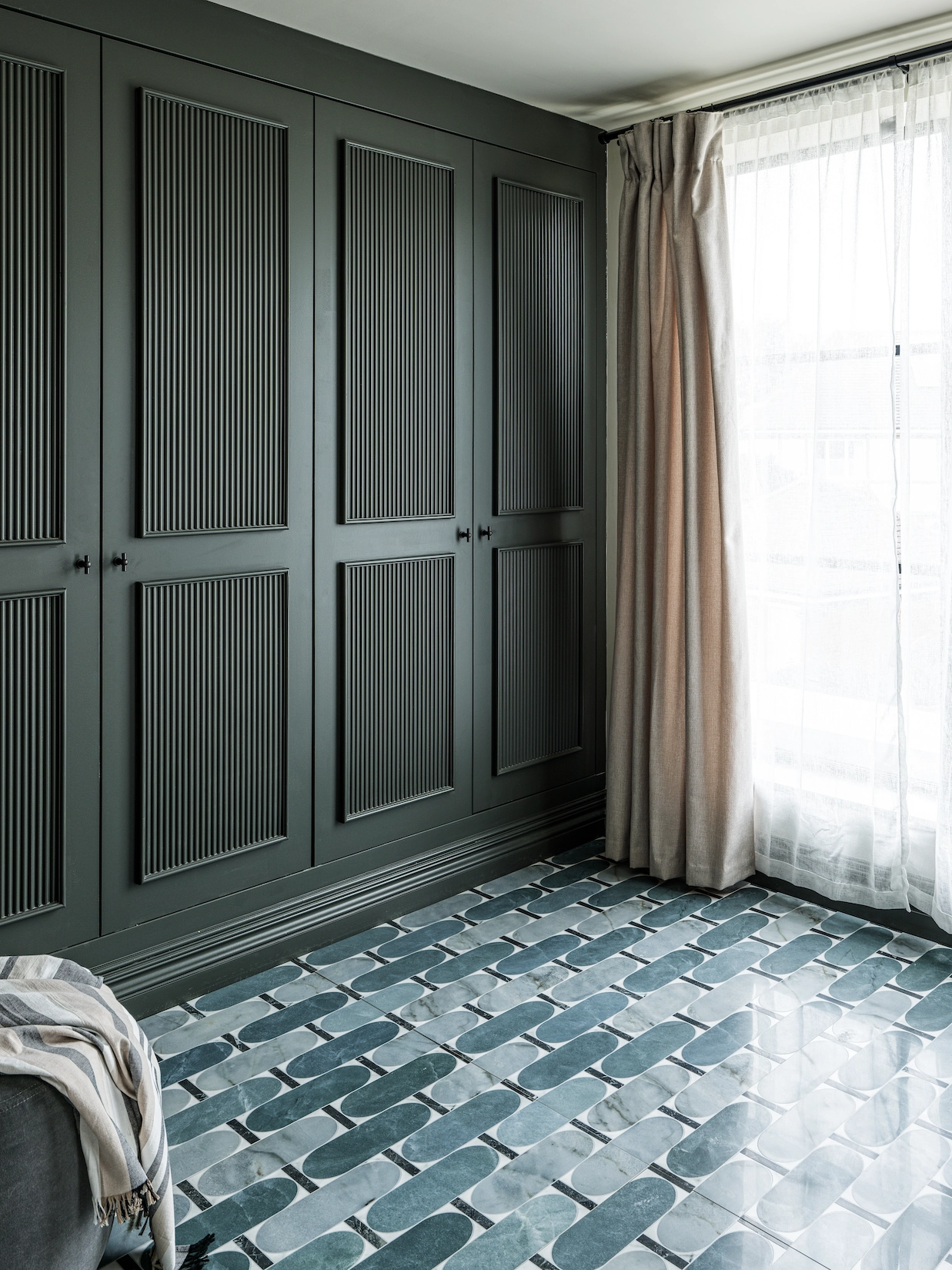 Green panelled fitted wardrobes with patterned tiled floor