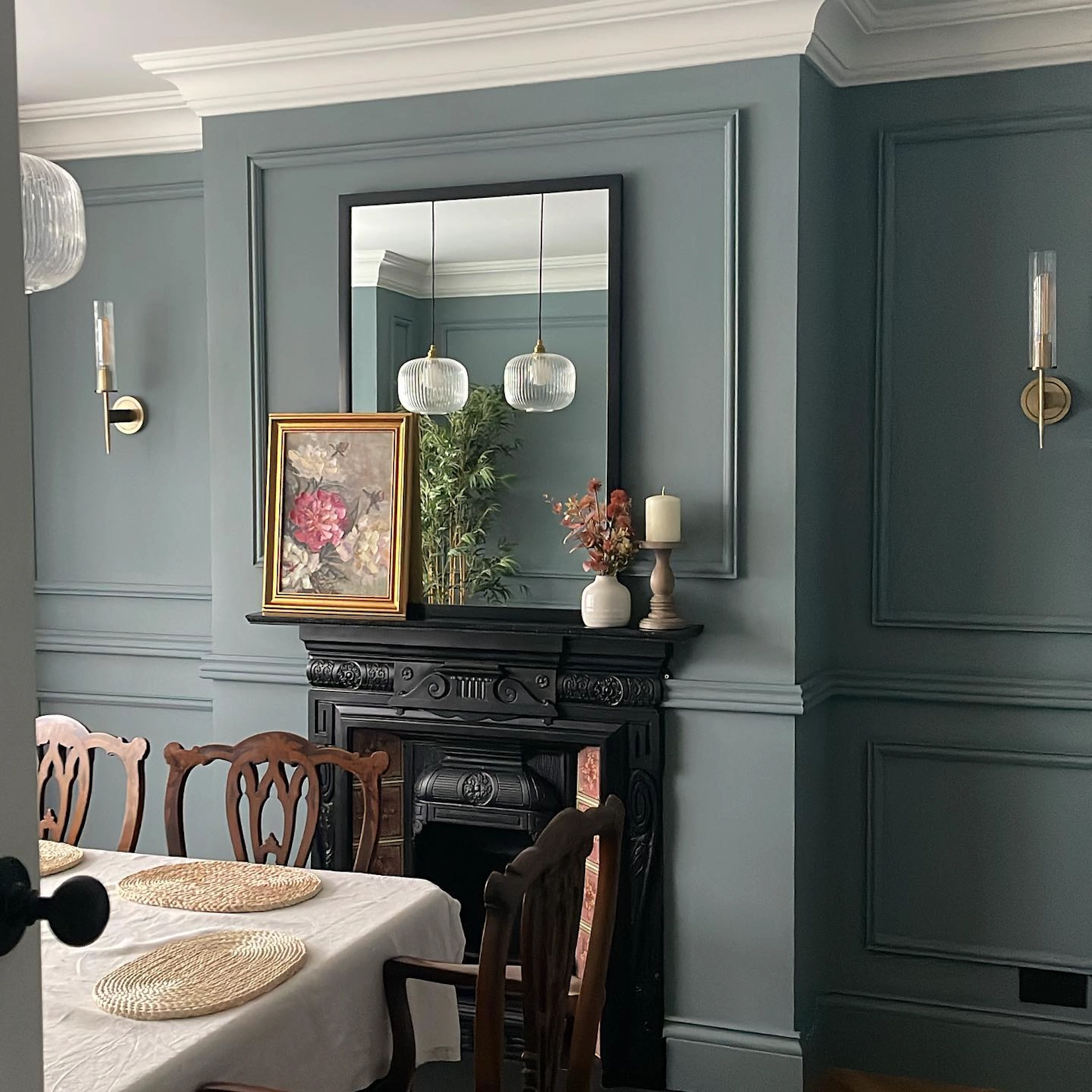 Panelled dining room in green with fireplace and antique mirror