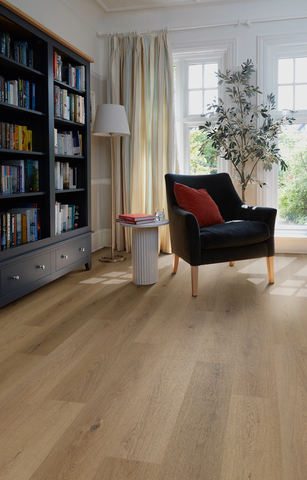 Fitted library shelving with armchair and oak flooring