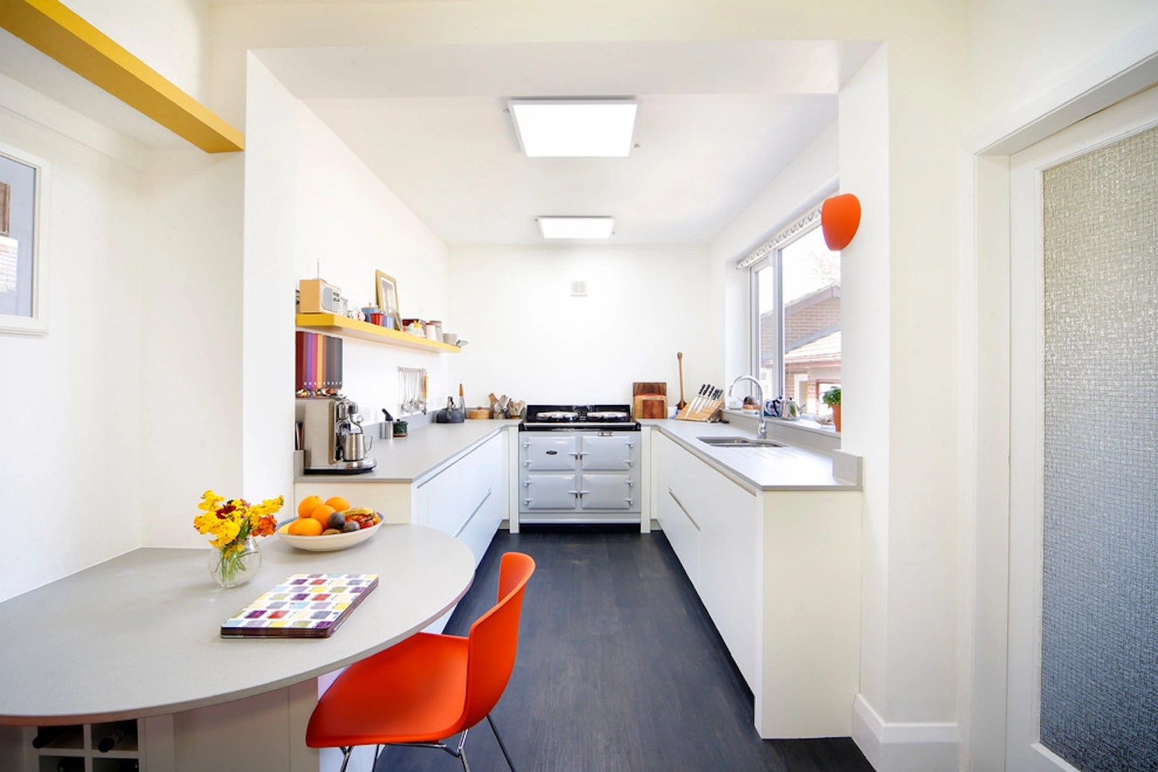 White handleless galley kitchen with breakfast table