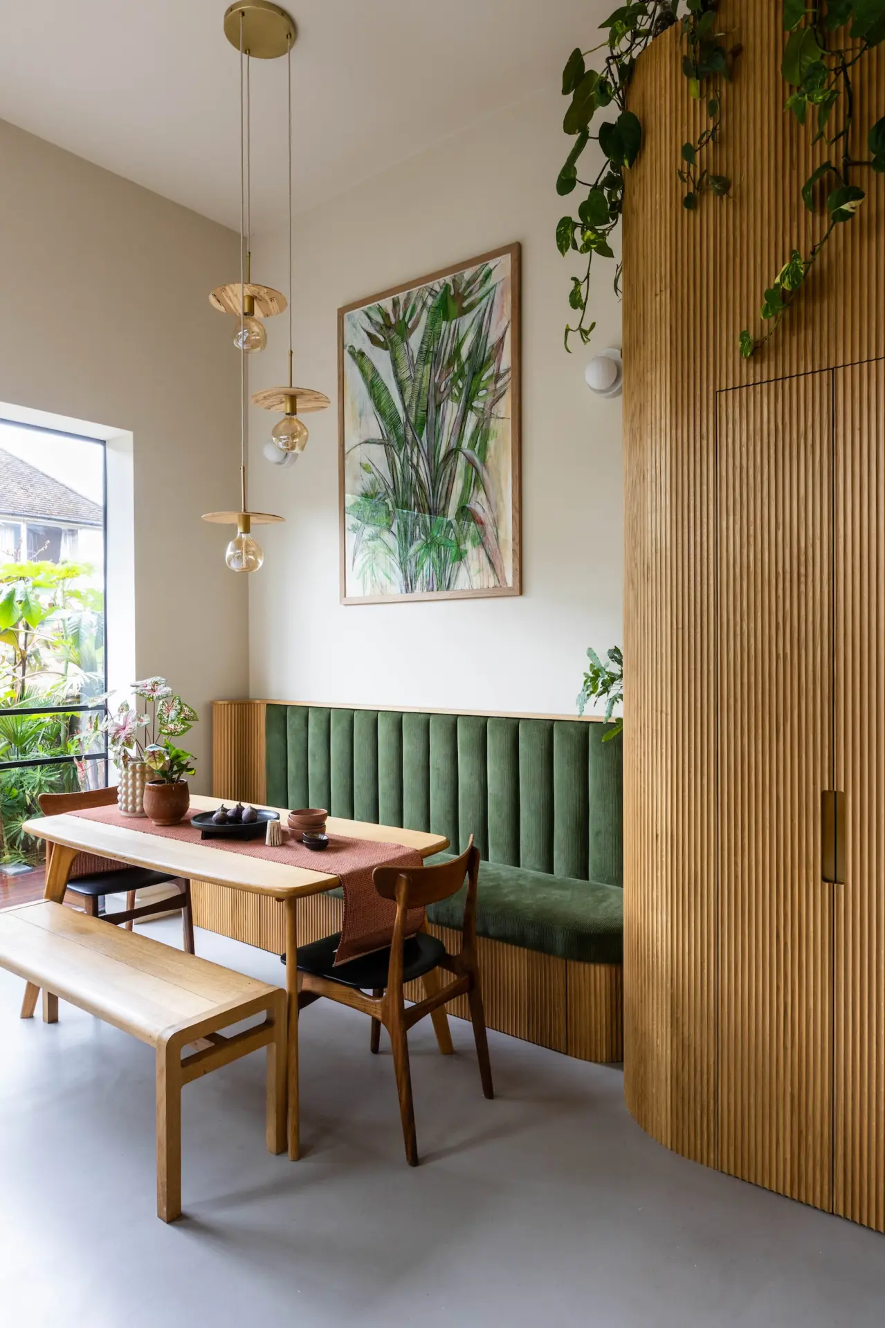 Dining area with green banquette seating and timber panelling