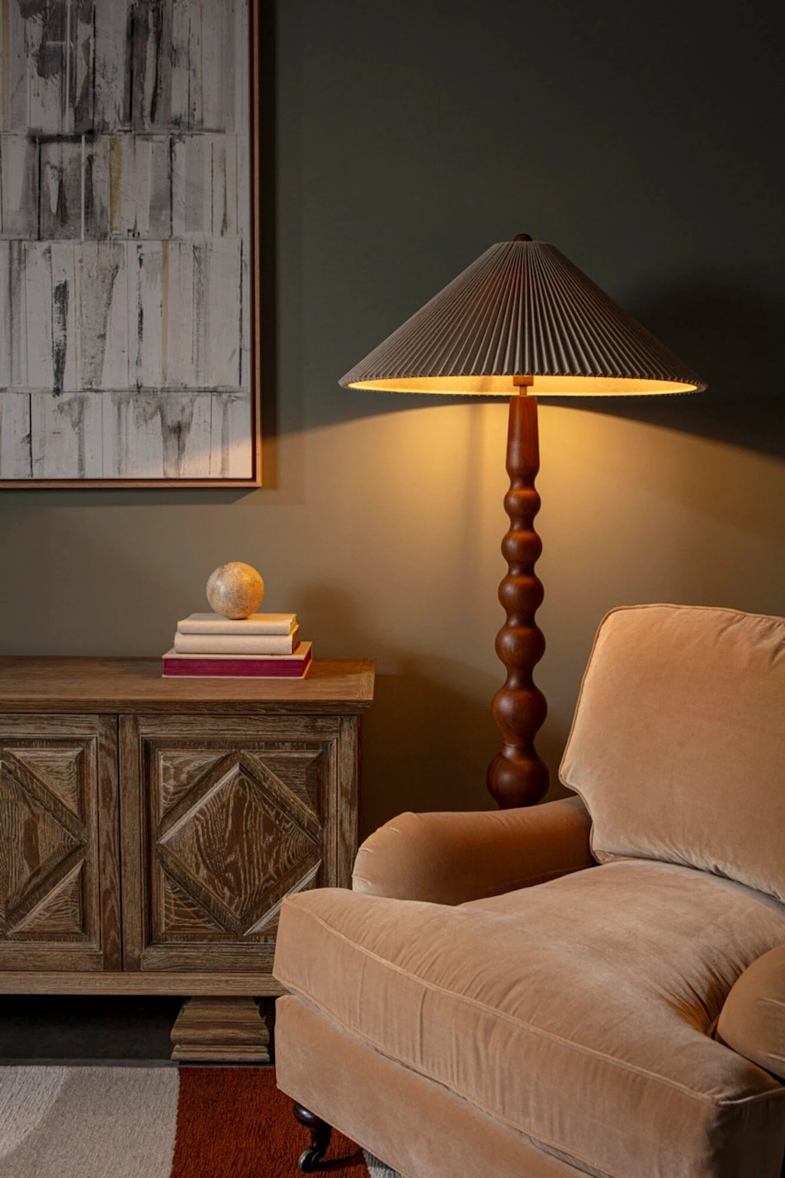Reading corner with turned floor lamp and velvet armchair