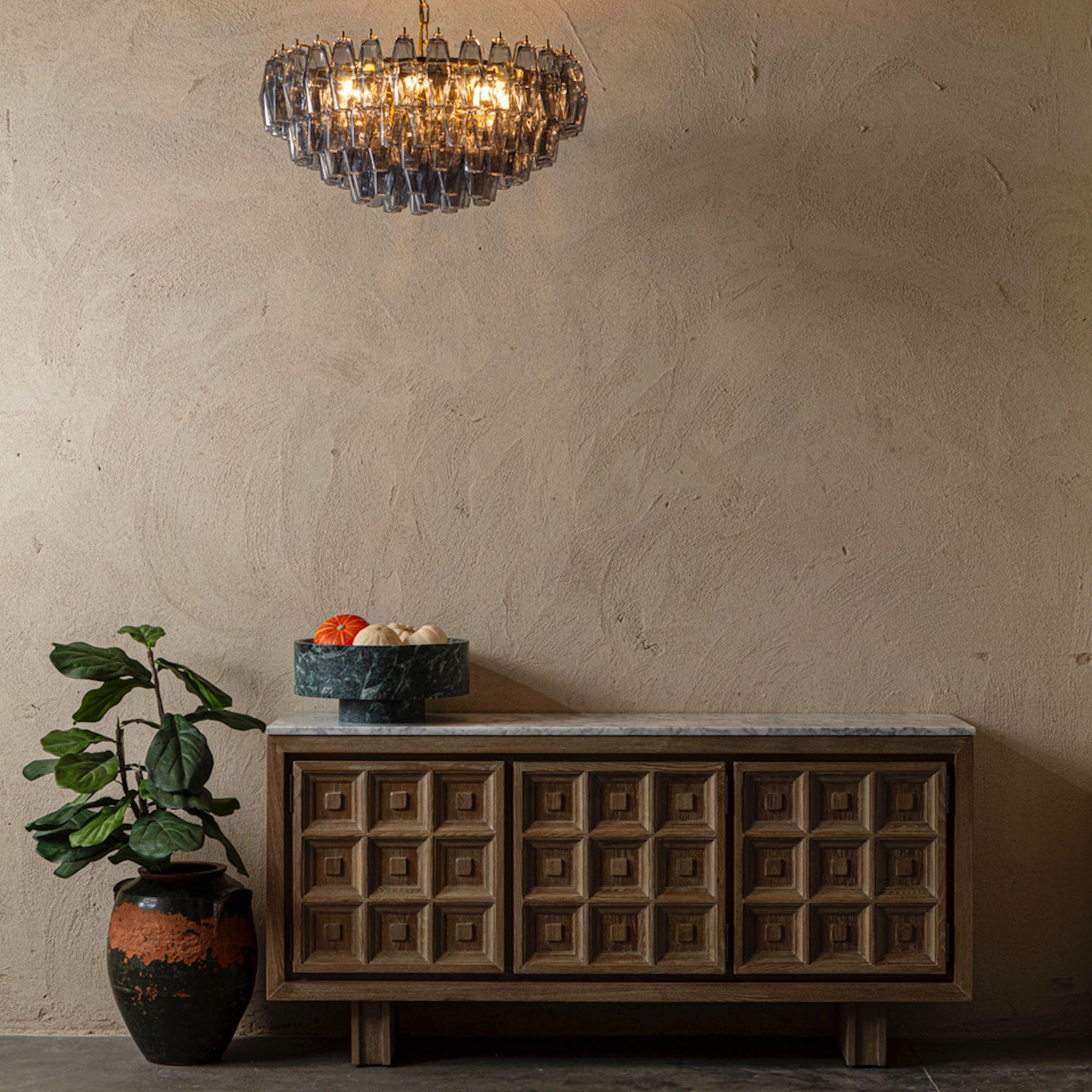 Carved timber sideboard against a plaster wall with chandelier