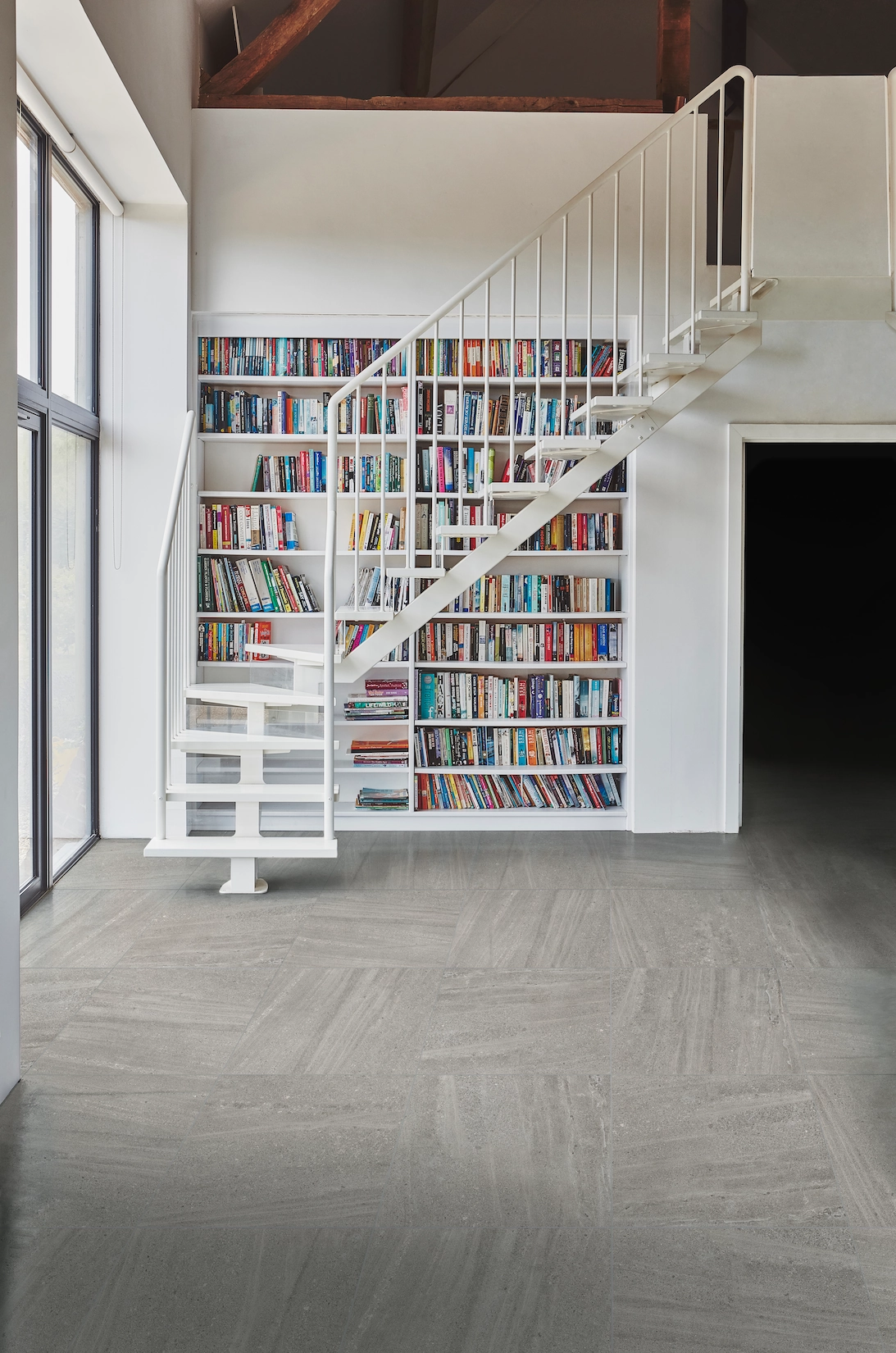 Double height library wall with staircase and herringbone floor