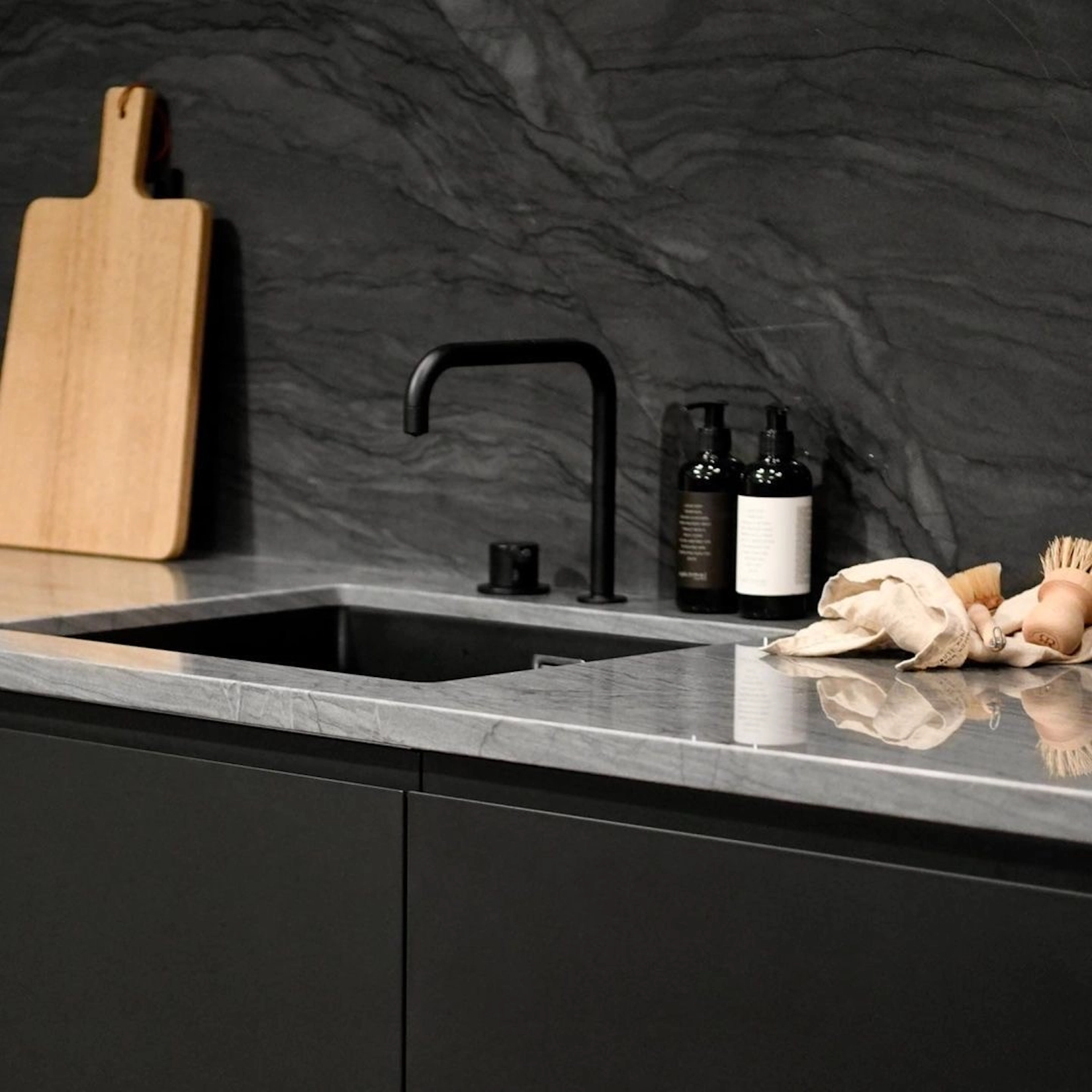 Black handleless kitchen with dark marble splashback