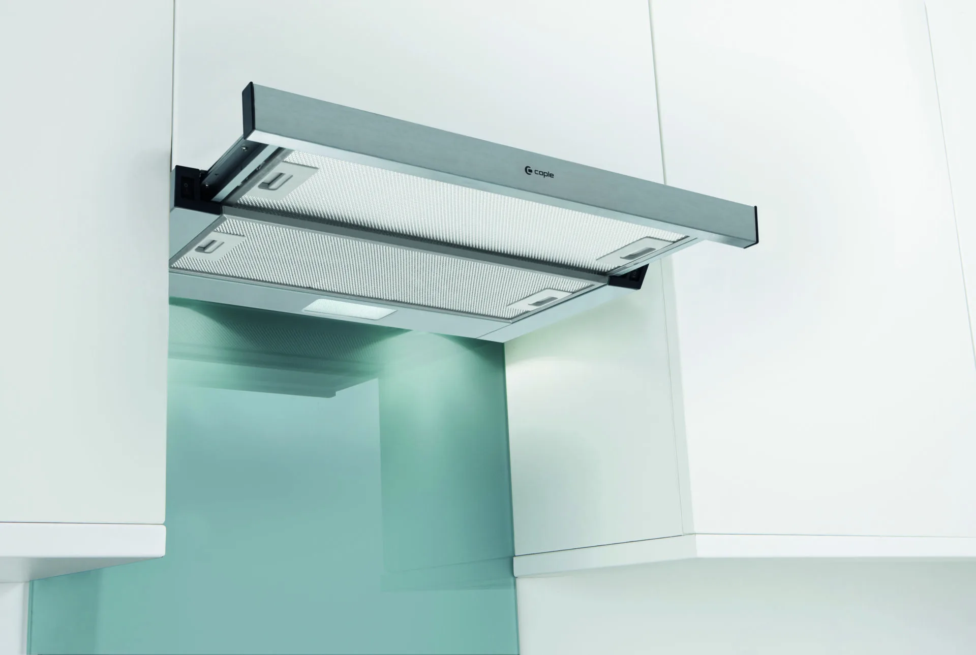 Stainless steel extractor hood above a pale green kitchen wall
