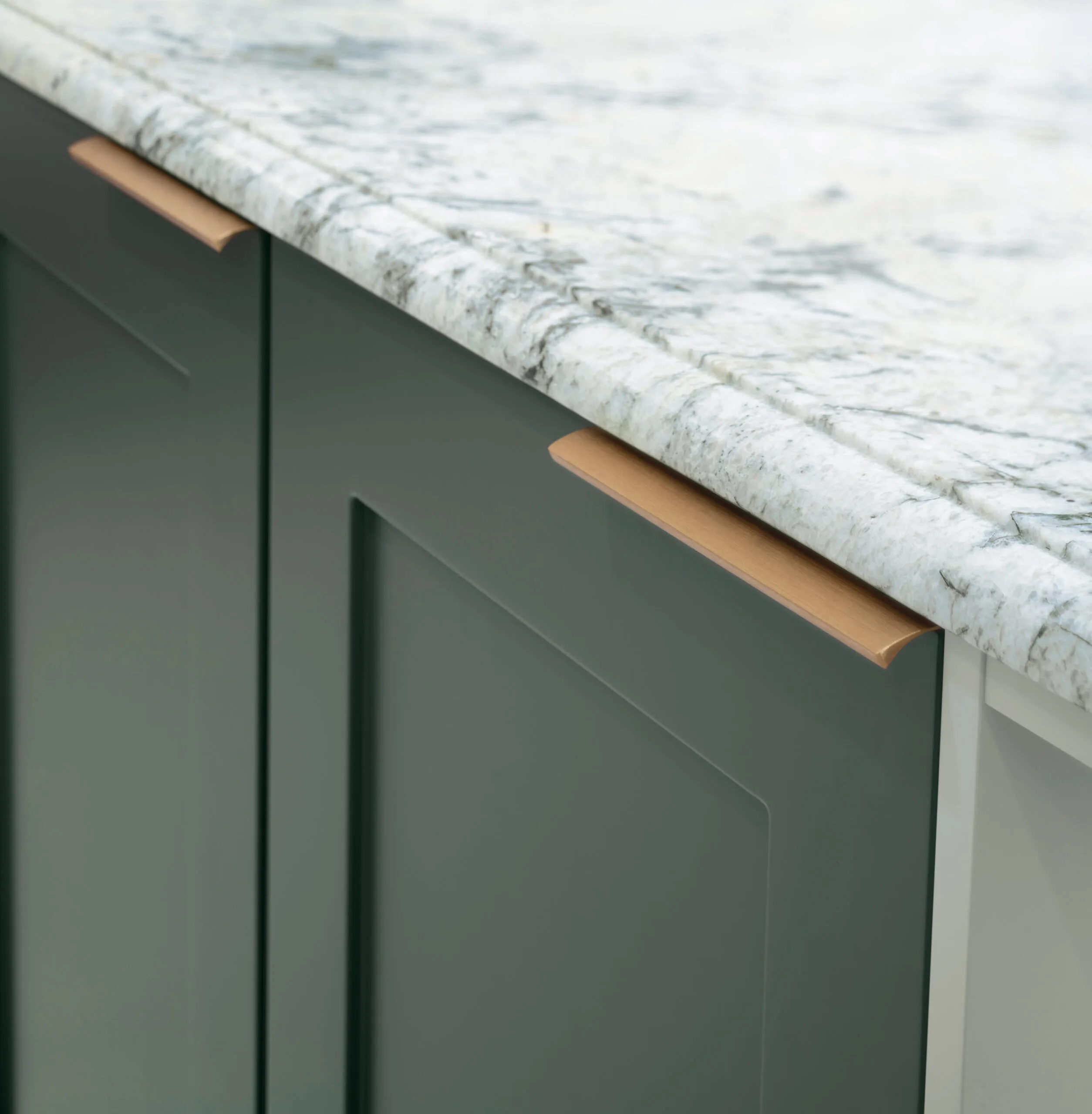 Brass trim handle on a green Shaker cabinet door