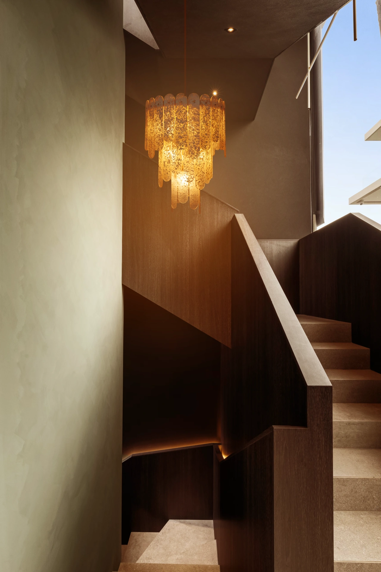 Staircase with bespoke timber panelling and crystal chandelier