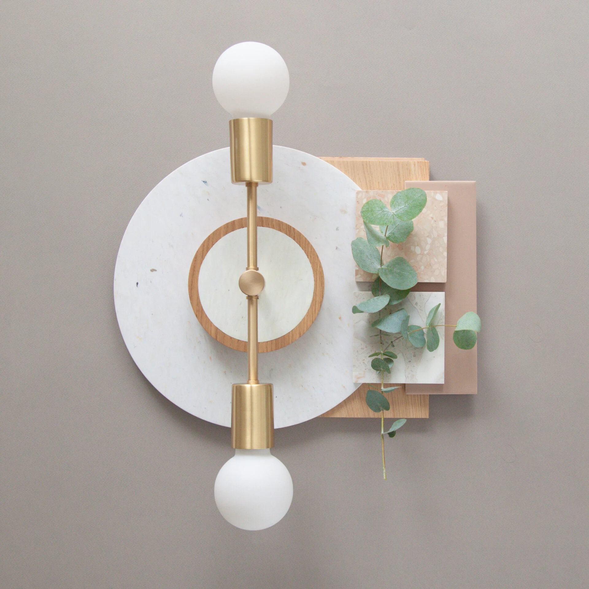 Brass wall light with material samples and eucalyptus