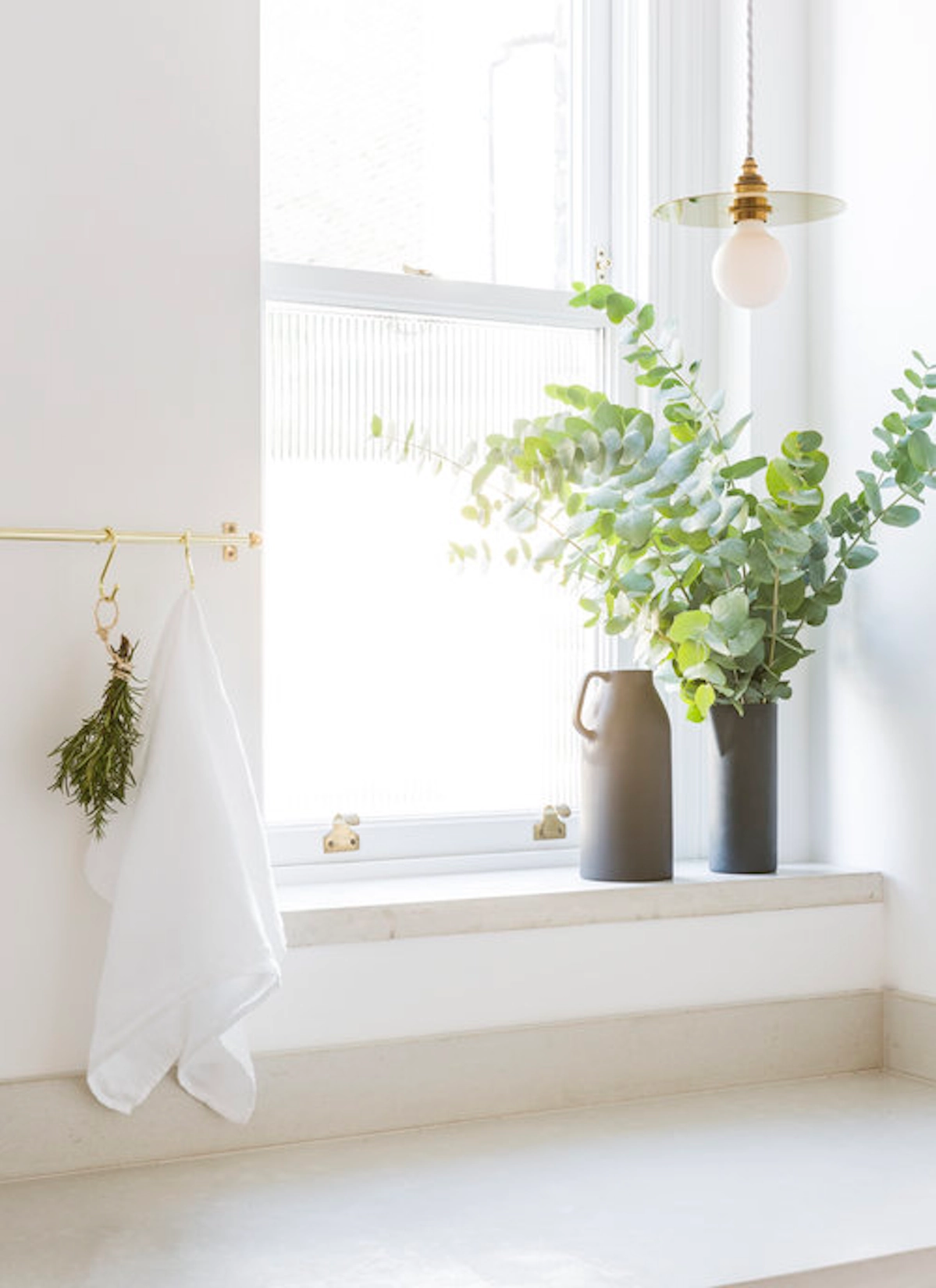 Window sill with stoneware vases and greenery