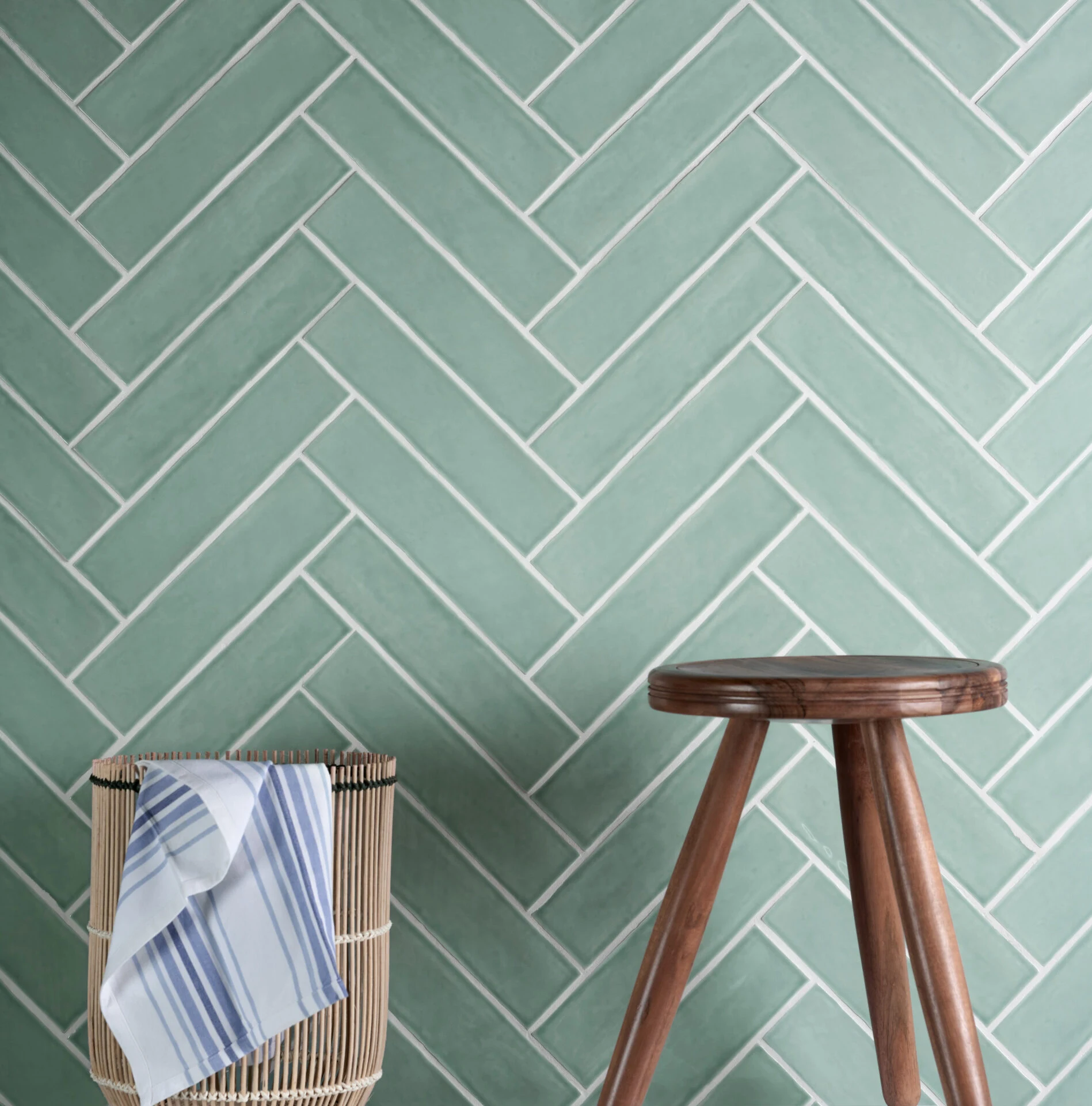 Green herringbone wall tiles with timber stool