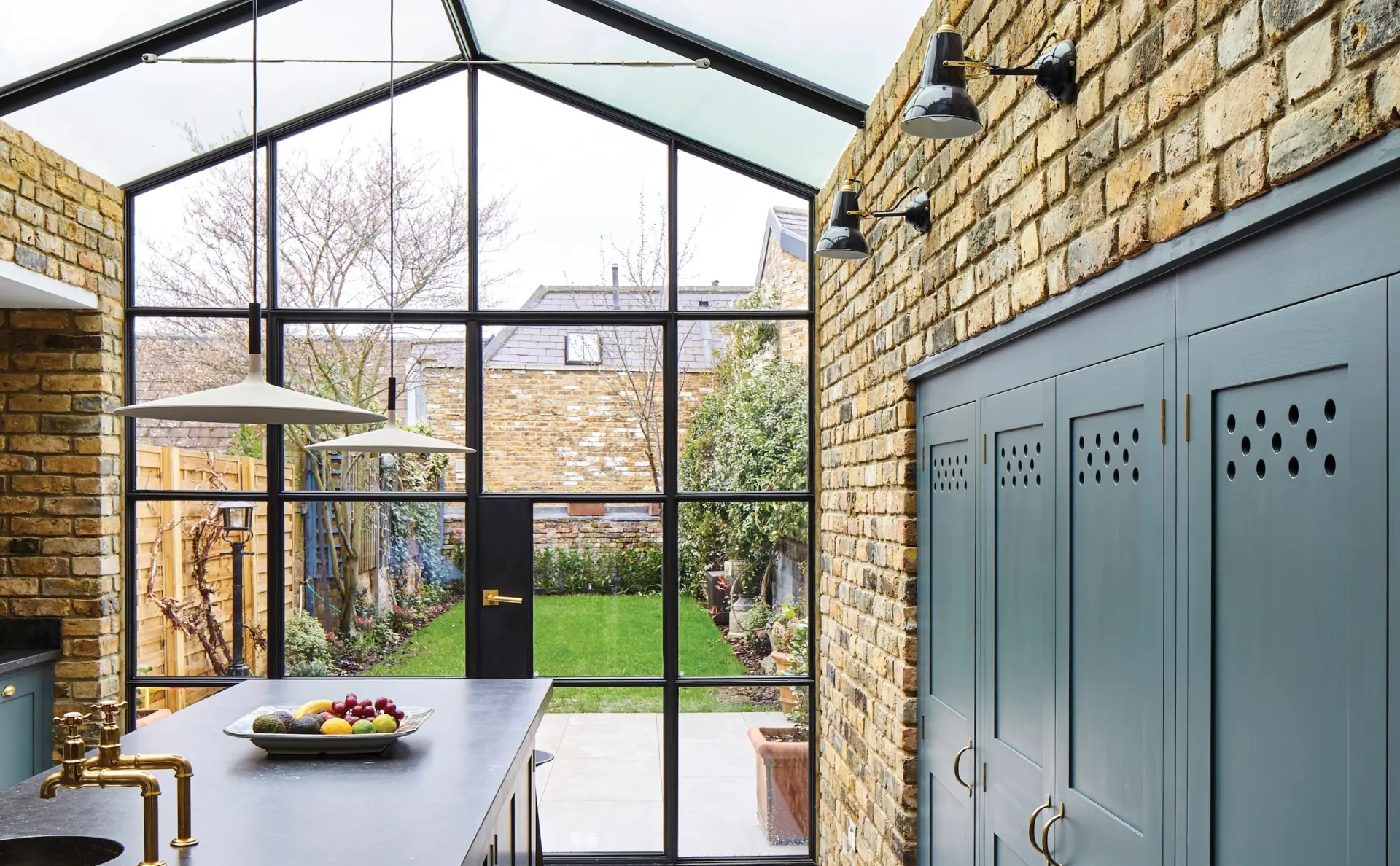 Kitchen extension with glazed roof, dark green cabinetry and garden doors