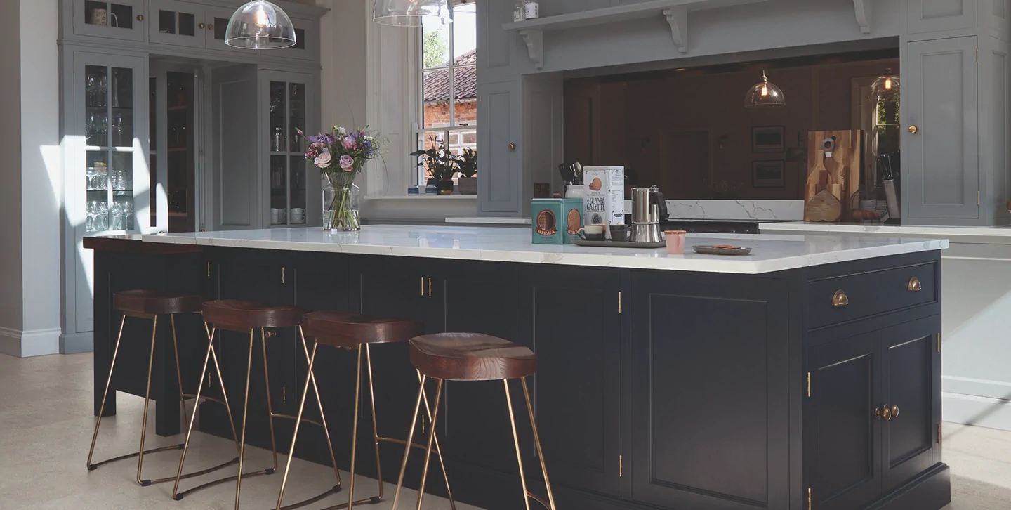Navy kitchen island with leather bar stools and pendant lighting